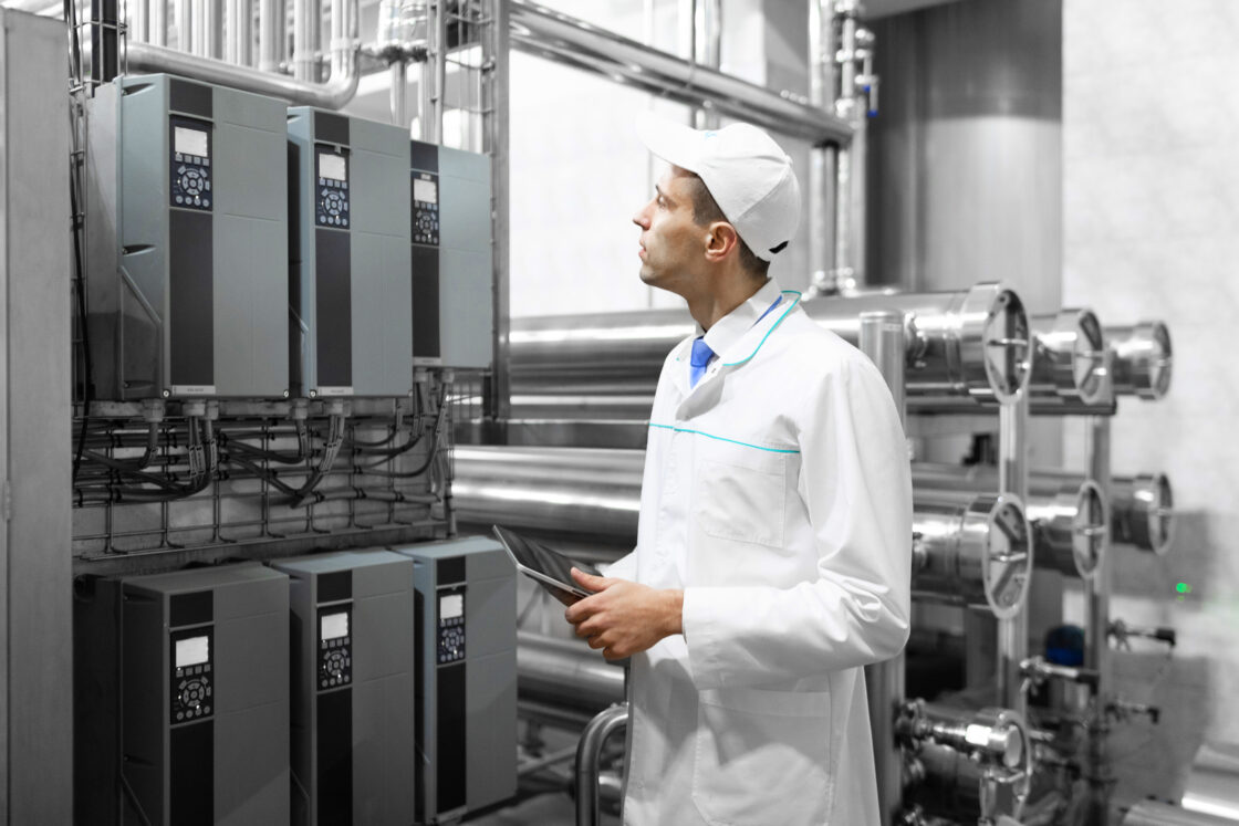 Um gestor de ESG fiscaliza os equipamentos e o ambiente industrial com um tablet com painel de controle nas mãos.