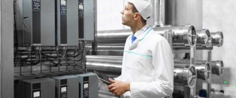 Um gestor de ESG fiscaliza os equipamentos e o ambiente industrial com um tablet com painel de controle nas mãos.
