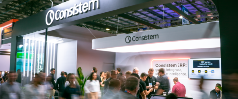 Estande da Consistem na Febratex 2026 bastante movimentado, com visitantes e especialistas conversando, e painel ao fundo destacando "Consistem ERP: gestão integrada, segura e inteligente".